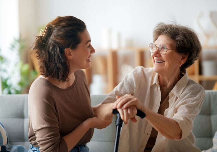 Happy patient and caregiver spending time together. Senior woman holding cane.