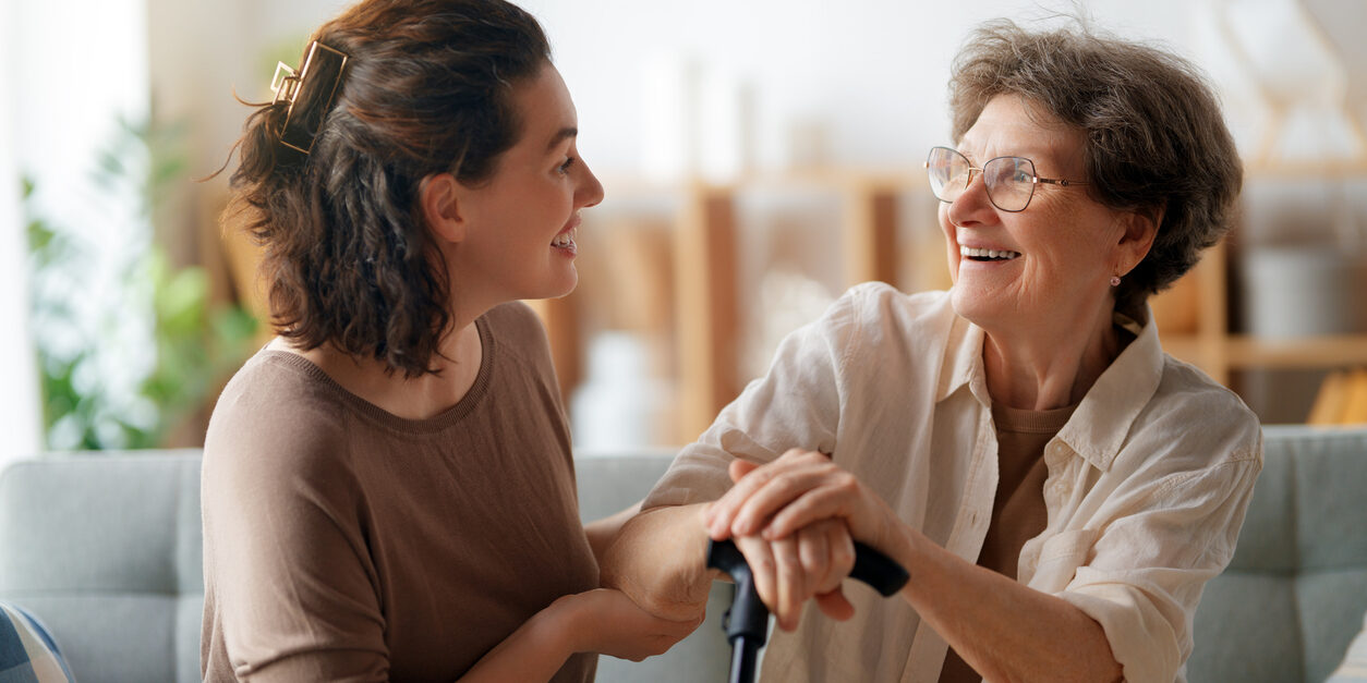 Happy patient and caregiver spending time together. Senior woman holding cane.