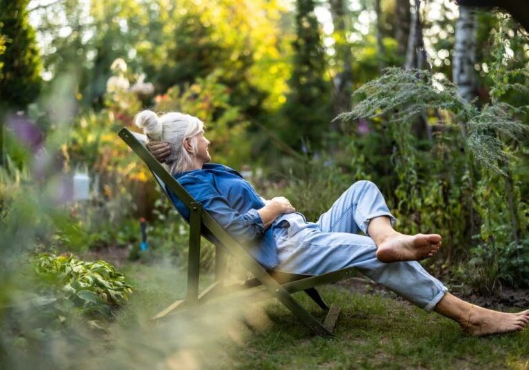 Mature woman relaxing in deckchair in her garden
