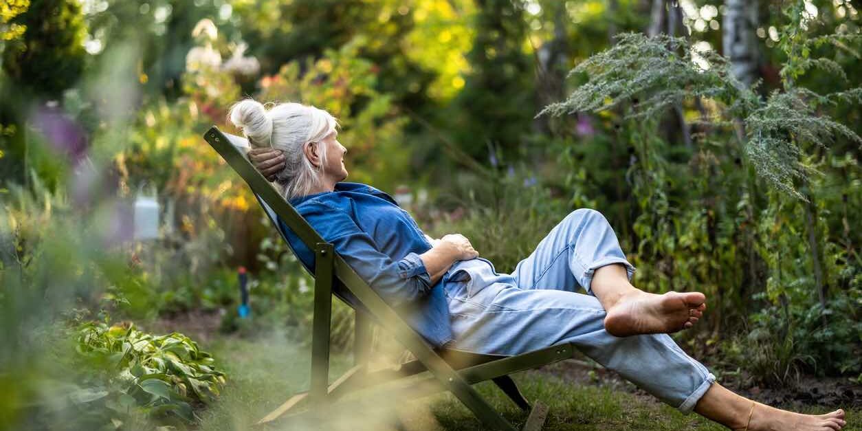 Mature woman relaxing in deckchair in her garden