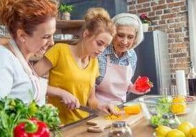 Happy three-generation family cooking together vegetable salad in kitchen